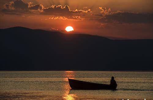 Маж во кајче на зајдисонце близу селото Трпејца на Охридското езеро